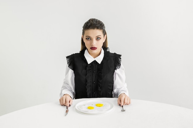 Foto gratuita somos lo que comemos. mujer comiendo huevos fritos de plástico, concepto ecológico. hay tantos polímeros que simplemente estamos hechos de ellos. desastre ambiental, moda, belleza, comida. perdiendo mundo orgánico.