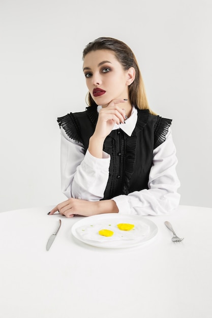 Somos lo que comemos. Mujer comiendo huevos fritos de plástico, concepto ecológico