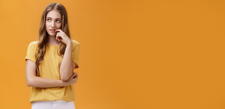 Foto gratuito soñadora y enfocada atractiva joven esbelta común con hermoso cabello ondulado tocando los labios mirando