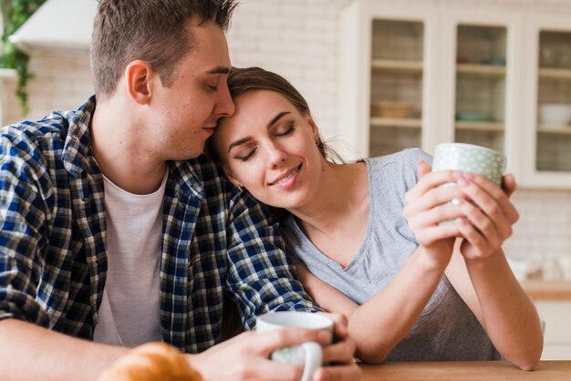 Soñadora pareja sentada en la mesa y tomando té