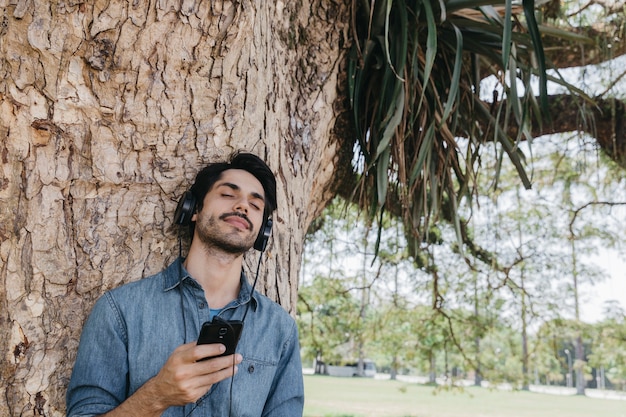 Foto gratuita soñando hombre disfrutando de la música en el parque