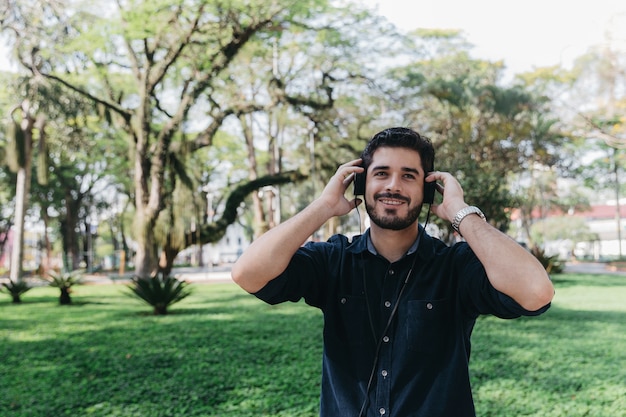 Soñando joven disfrutando de la música en el parque