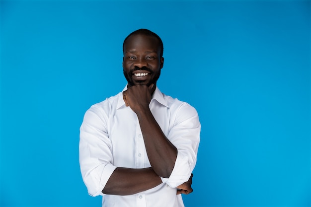 Sonriendo afroamericano en camisa blanca sobre fondo azul