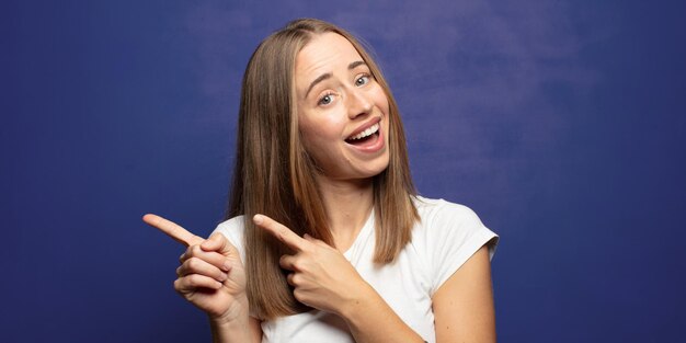 sonriendo alegremente y señalando para copiar el espacio en la palma de la mano en el lado mostrando o anunciando un objeto