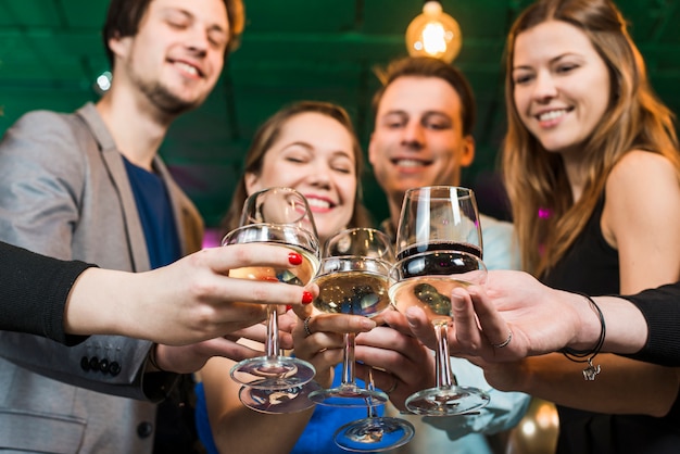 Sonriendo amigos hombres y mujeres brindando cócteles en una fiesta en el bar