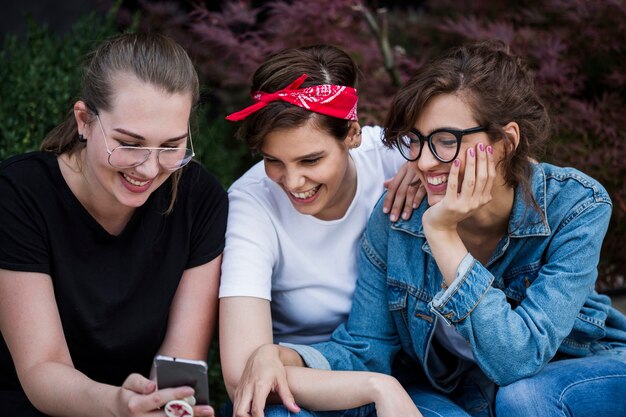 Sonriendo amigos mirando la pantalla del teléfono inteligente