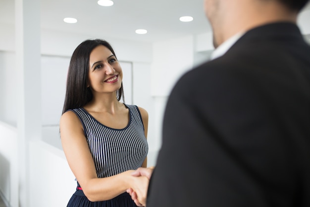 Foto gratuita sonriendo atractiva empresaria haciendo apretón de manos con pareja