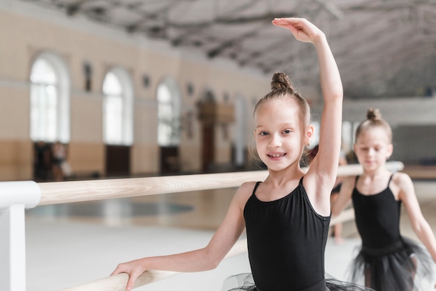 Sonriendo bailarín de ballet practicando con barre en clase de baile