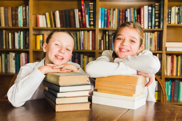Foto gratuita sonriendo chicas sentadas con montones de libros
