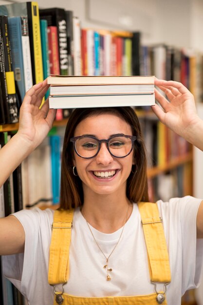 Sonriendo colegiala adolescente con libros en la cabeza