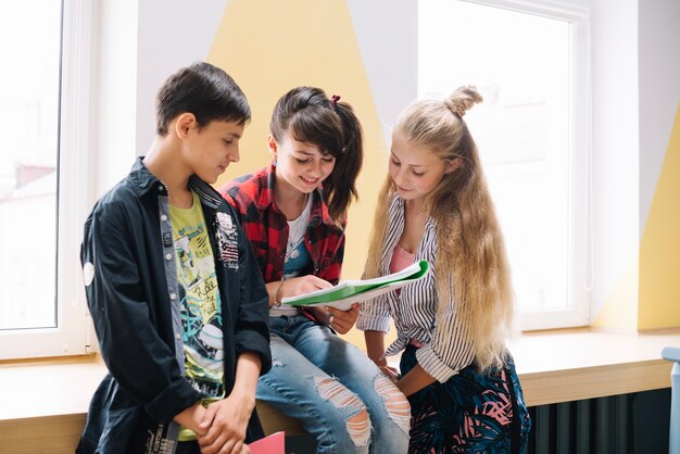 Sonriendo compañeros de clase con el libro de texto