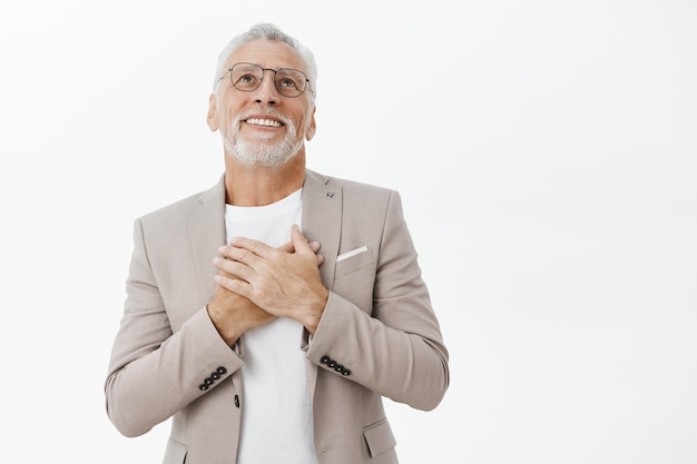 Sonriendo complacido y feliz hombre senior en traje mirando encantado