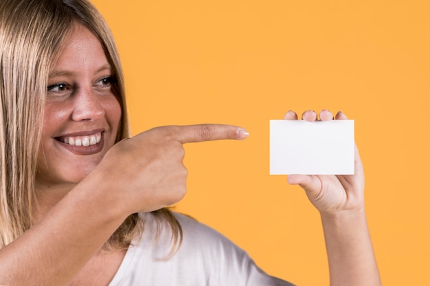 Foto gratuita sonriendo deshabilitar joven apuntando sobre tarjeta de visita en blanco