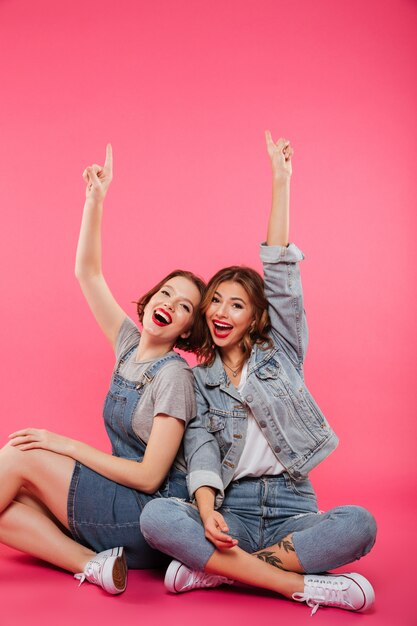 Sonriendo dos amigas sentadas en el piso