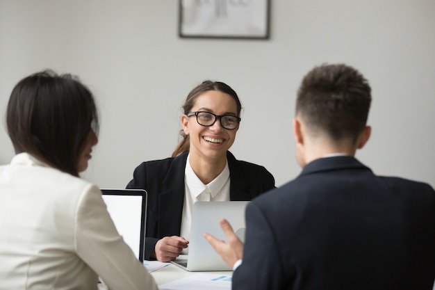 Sonriendo empresaria hablando con subordinados sobre informes