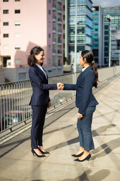 Sonriendo empresarias estrechándole la mano