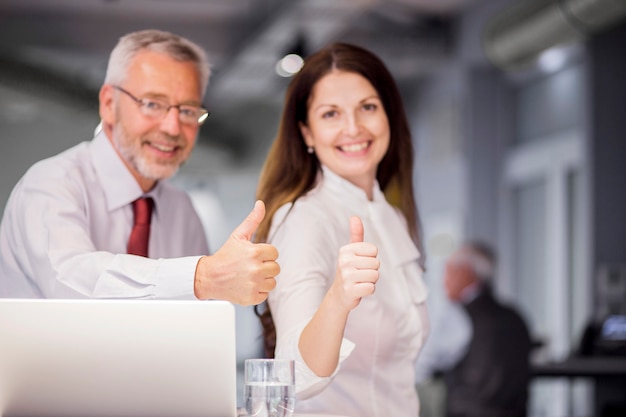 Sonriendo empresarios exitosos mostrando pulgar arriba firman en la oficina