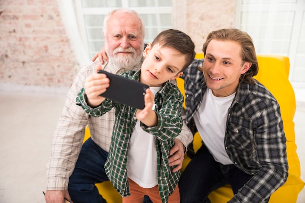 Foto gratuita sonriendo familia multigeneracional tomando selfie con smartphone