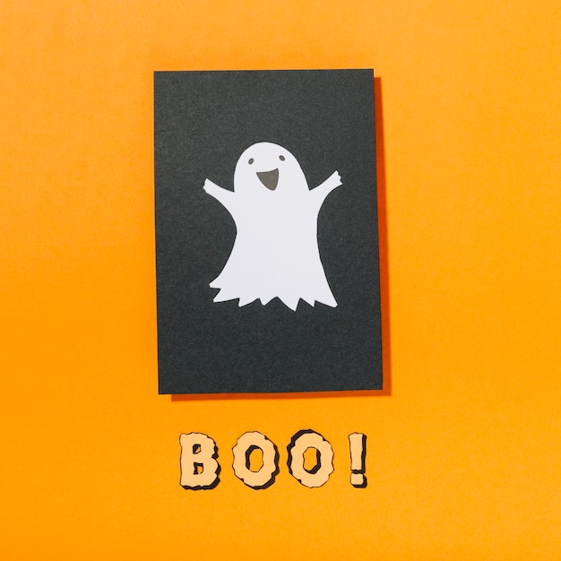 Foto gratuita sonriendo fantasma en papel negro con boo! inscripción abajo