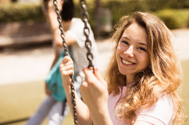 Sonriendo feliz colegiala sentada en columpios