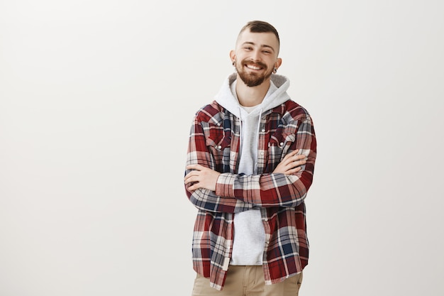 Sonriendo feliz hipster chico brazos cruzados en el pecho confiado y riendo