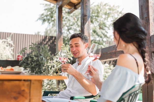 Sonriendo feliz pareja joven disfrutando del vino en el jardín