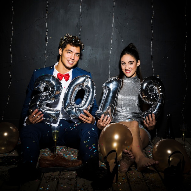 Foto gratuita sonriendo feliz pareja con números de globos