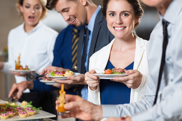 Sonriendo gente de negocios y aperitivos en la Tabla Buffet