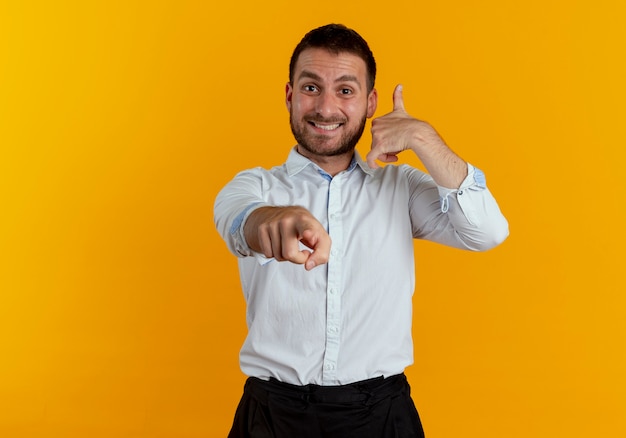 Foto gratuita sonriendo gestos de hombre guapo me llaman signo de mano apuntando aislado en la pared naranja