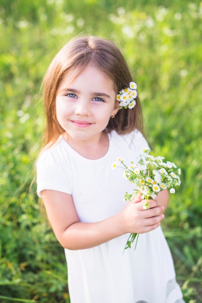 Sonriendo a hermosa chica sosteniendo ramo de flores blancas