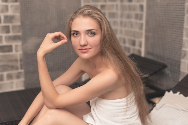 Foto gratuita sonriendo a hermosa mujer joven sentada en el sillón en el spa