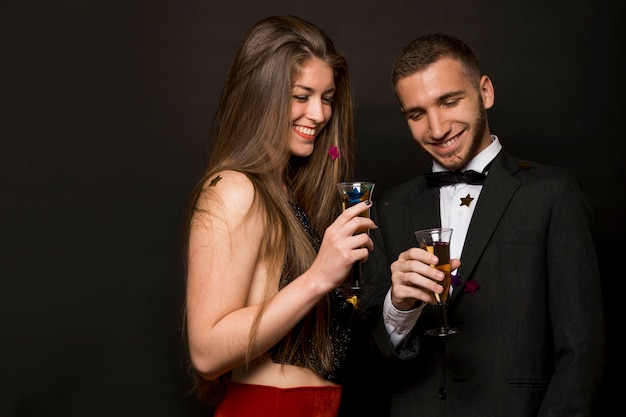 Sonriendo hombre y mujer con copas de bebidas y confeti
