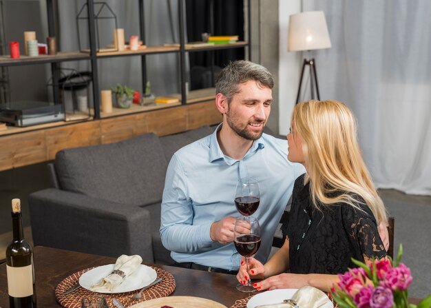 Sonriendo el hombre y la mujer con copas de vino en la mesa