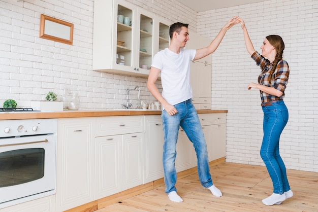 Sonriendo hombre y mujer enamorados bailando en la cocina