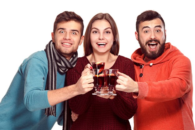 Sonriendo a hombres y mujeres europeos durante la sesión de fotos de la fiesta. chicos haciéndose pasar por amigos en el festival de estudio con copas con vino caliente caliente en primer plano.