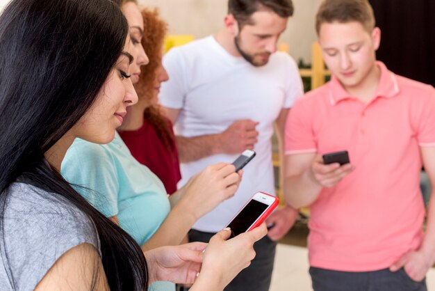 Sonriendo hombres y mujeres usando teléfonos celulares