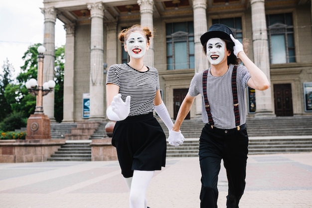 Sonriendo mime pareja corriendo frente al edificio