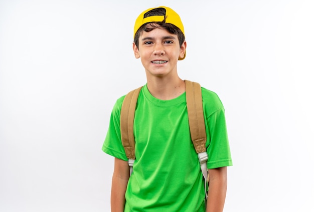 Foto gratuita sonriendo mirando cámara joven escolar vistiendo mochila con gorra