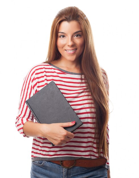 Sonriendo morena de pelo largo que sostiene el cuaderno negro