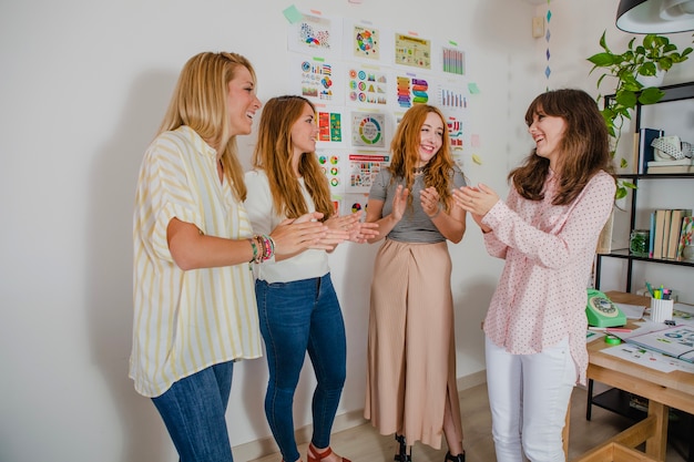 Foto gratuita sonriendo a las mujeres aplaudiendo en la oficina