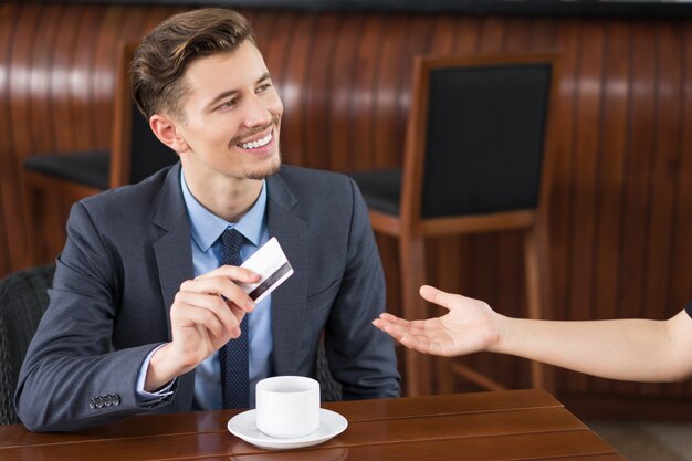 Sonriendo de negocios que paga con tarjeta de crédito en el Café