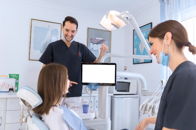 Sonriendo paciente y dentista teniendo una conversación en clínica dental