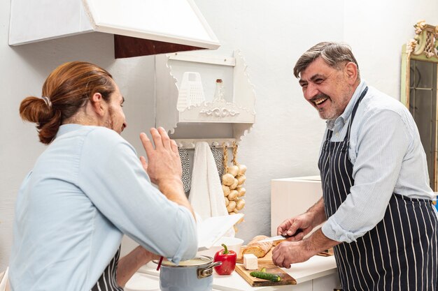 Sonriendo padre e hijo cocinando y mirándose