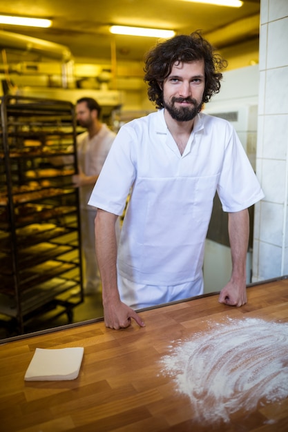 Sonriendo panadero coloca en el contador de trabajo