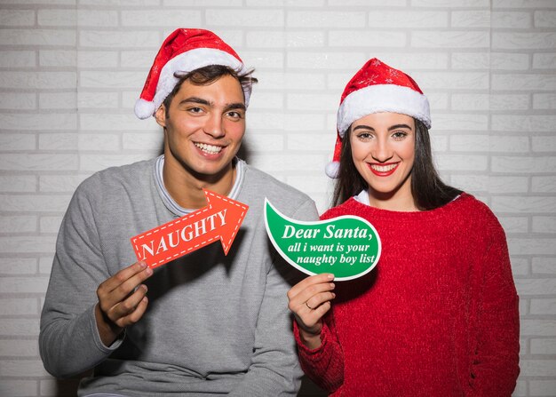Sonriendo pareja festiva con diferentes signos de Navidad