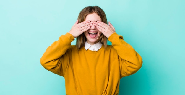 Sonriendo y sintiéndose feliz cubriendo los ojos con ambas manos y esperando una sorpresa increíble