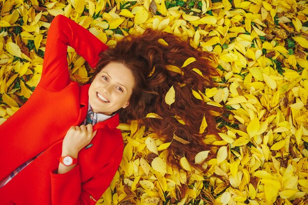 Sonriendo womn hojas de otoño en el cabello