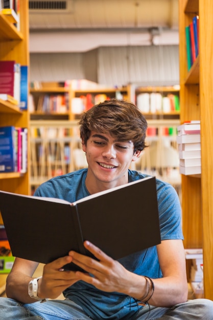 Sonriente adolescente leyendo en el piso