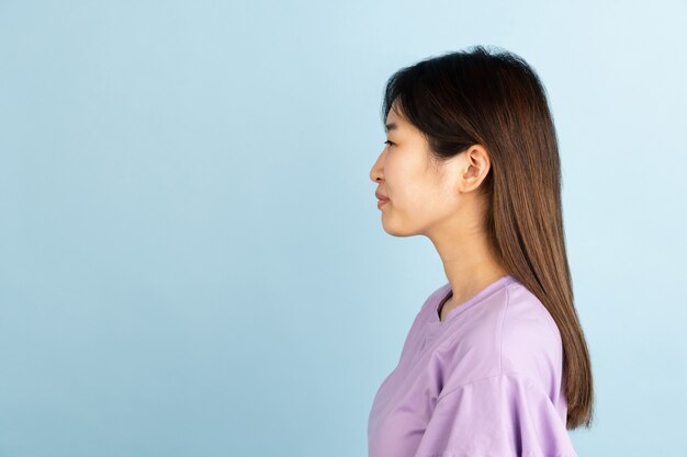 Sonriente, alegre. Retrato de mujer joven asiática en pared azul. Modelo de mujer hermosa en estilo casual. Concepto de emociones humanas, expresión facial, juventud, ventas, publicidad.