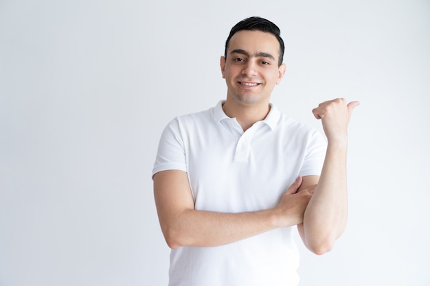 Sonriente apuesto joven apuntando el pulgar a un lado. Chico recomendando algo.